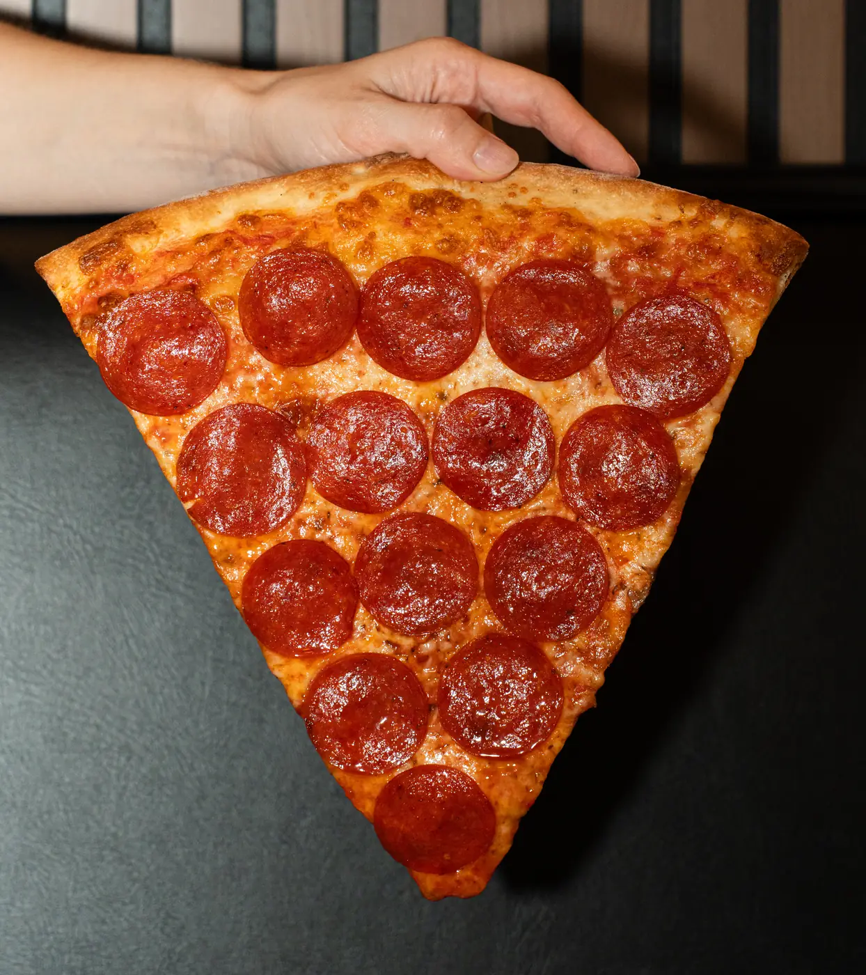 Hand holding a New York pepperoni slice — Times Square Pizza
